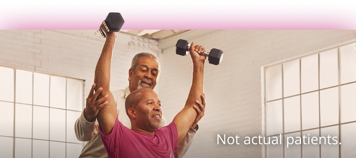 One man helping another man lift weights. Not actual patients. 